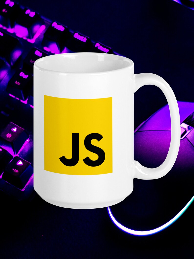 Pu&ograve; includere: Una tazza in ceramica bianca con un quadrato giallo che presenta le lettere "JS" in nero. La tazza &egrave; su una superficie nera con una tastiera e un mouse viola sullo sfondo.
