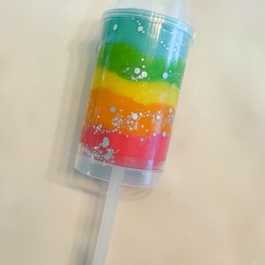 May include: A clear plastic push pop container filled with layers of colorful rainbow-colored slime. Silver glitter is sprinkled throughout the layers. The container has a clear lid and a clear plastic stick.