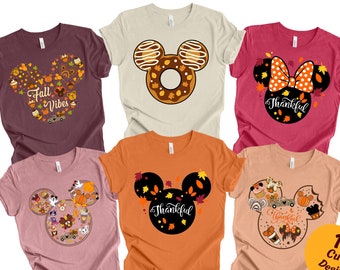 May include: Twelve different designs of t-shirts featuring a Mickey Mouse silhouette with various fall-themed designs. The designs include a donut, a bow, and a variety of fall-themed icons. The text "Thankful" appears on some of the designs.