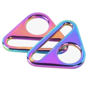 Puede incluir: Dos anillos triangulares de metal iridiscente con un agujero en el centro de cada uno. Los anillos se superponen.