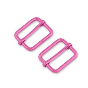 May include: Two pink metal slider buckles. The buckles are rectangular with a rounded edge and have a smooth finish.
