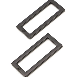 May include: Two black metal rectangular rings with rounded corners. The rings are about 2 inches long and 1 inch wide.