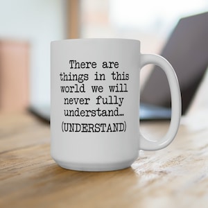May include: White ceramic coffee mug with a black text quote that reads "There are things in this world we will never fully understand... (UNDERSTAND)"