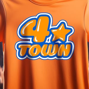 Può includere: Maglietta arancione con la scritta "4*TOWN" in un design blu e bianco. La maglietta è appesa a una gruccia di legno. Lo sfondo mostra una folla di persone e luci del palco.