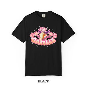 May include: Black t-shirt featuring a cartoon gazelle with musical notes and stars. The word "Gazelle" is written in a bubble font. The gazelle has blonde hair and purple horns. The word "BLACK" is written at the bottom.