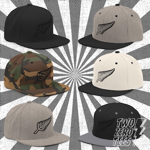 Könnte beinhalten: Sechs Baseballkappen mit flachem Schirm in verschiedenen Farben, darunter Schwarz, Grau, Camouflage und Weiß. Jede Kappe zeigt ein schwarzes Farnblatt-Design. Die Kappen haben eine strukturierte Passform und einen flachen Schirm.