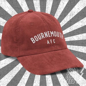 Può includere: Un berretto da baseball in velluto a coste rosso con testo ricamato bianco che recita "BOURNEMOUTH AFC".