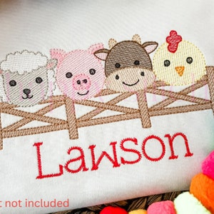 May include: Embroidered design of a pig, sheep, cow, and chicken peeking over a brown fence with the name Lawson stitched in red below.