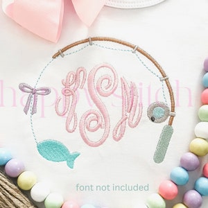 May include: A white onesie with a pink, blue, and green embroidered design of a fishing rod, a fish, and a bow. The design is in the shape of a circle and includes the monogram "FSL".