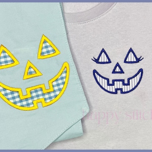 May include: Two items with jack-o'-lantern designs. One is a light blue fabric with a yellow-outlined face and blue gingham details. The other is a gray t-shirt with a blue embroidered jack-o'-lantern face. The designs are for Halloween.