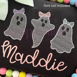 May include: A black t-shirt with three embroidered ghosts wearing pink bows. The text "Maddie" is embroidered in pink below the ghosts.