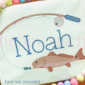 May include: Embroidered design of a fishing rod and reel with a fish on a light green background. The name "Noah" is embroidered in blue thread below the fishing rod.