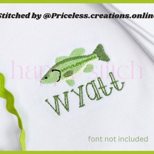May include: White fabric with green embroidered text "WYATT" and a green embroidered bass fish. The text "Stitched by @Priceless.creations.online" is at the top of the fabric. The text "font not included" is at the bottom of the fabric.