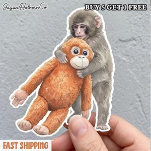 May include: A sticker featuring a watercolor illustration of two monkeys. One gray monkey hugs an orange monkey. The sticker has the text "Jason Holman Co" and "BUY 5 GET 1 FREE".