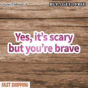 May include: A white sticker with the text "Yes, it's scary but you're brave" in pink glitter lettering. The sticker is on a brown wooden background. The words "BUY 5 GET 1 FREE" are at the top, and "FAST SHIPPING" is at the bottom.