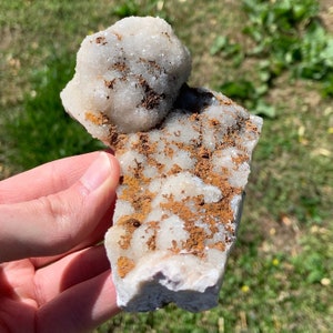 May include: A white crystal cluster with brown inclusions. The crystal is rough and has a natural, earthy look.
