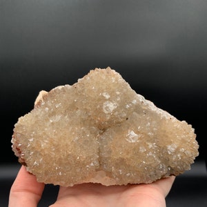 May include: A cluster of light brown quartz crystals with a rough, natural texture. The crystals are clustered together in a dense formation, creating a unique and interesting shape.