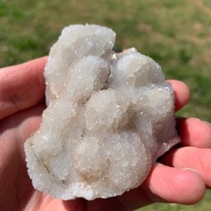 May include: A cluster of white quartz crystals with a rough, natural texture. The crystals are clustered together in a dense formation, creating a unique and interesting shape.