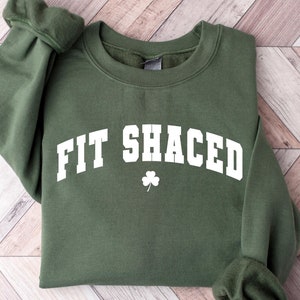 May include: Green sweatshirt with white text that reads "Fit Shaced" with a shamrock symbol.