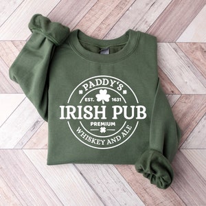 May include: Green sweatshirt with a white circular design that says "Paddy's Irish Pub Premium Whiskey and Ale" with a shamrock and "Est. 1631" inside the circle.