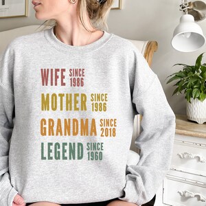 a woman sitting on a couch wearing a sweatshirt