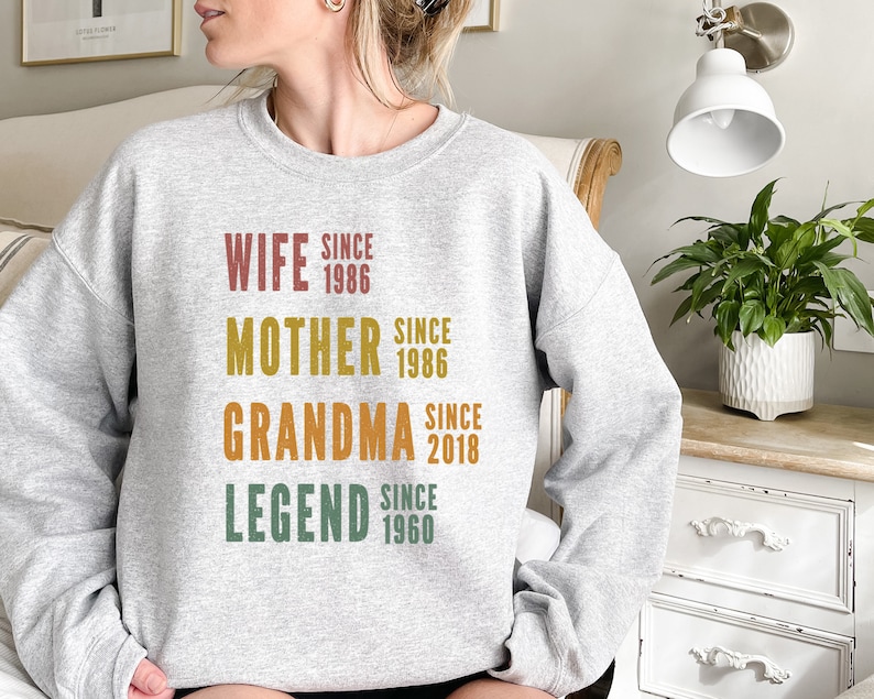 a woman sitting on a couch wearing a sweatshirt