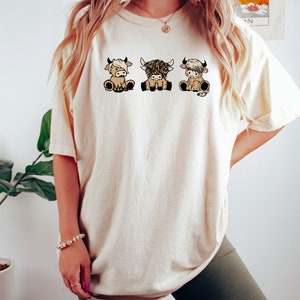 a woman wearing a white shirt with three cows on it