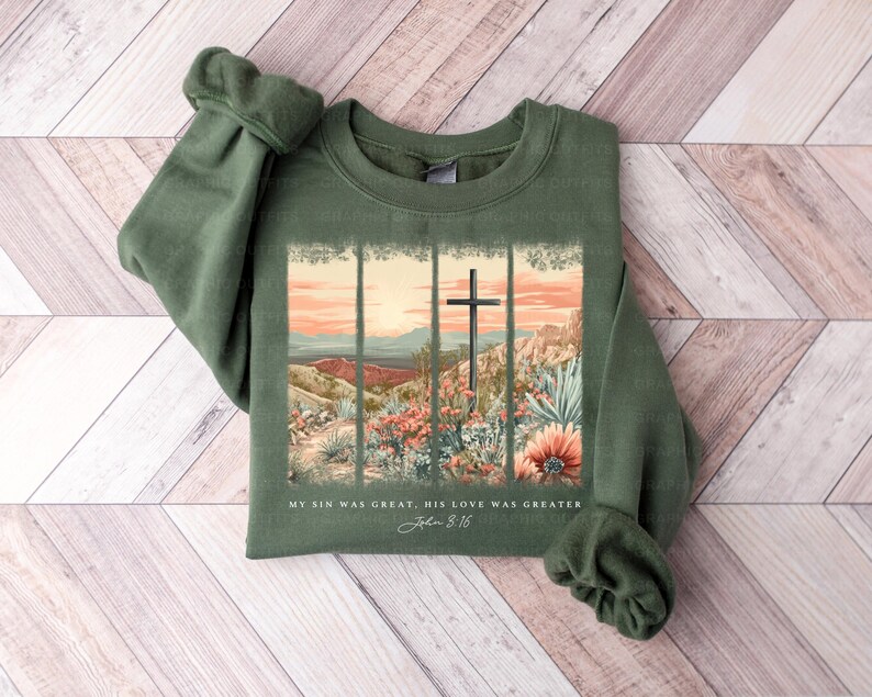Puede incluir: Una sudadera verde con un dise&ntilde;o de cruz y flores. El texto en la sudadera dice "My sin was great, His love was greater John 3:16".