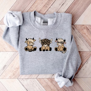 a gray sweater with three cows on it