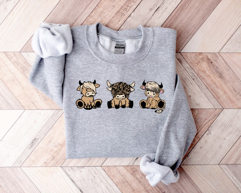 a gray sweater with three cows on it
