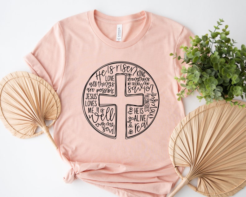 a pink t - shirt with a cross on it