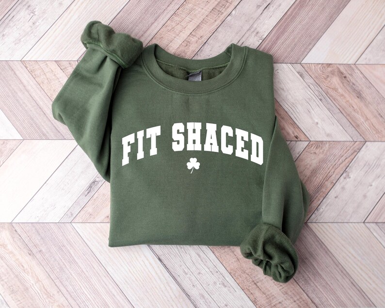 May include: Green sweatshirt with white text that reads "Fit Shaced" with a shamrock symbol.