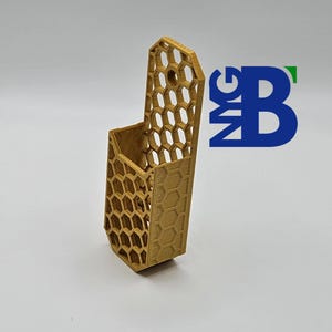 May include: A gold-coloured 3D printed wall mount with a honeycomb pattern. The mount has a small opening at the top and a larger opening on the side.