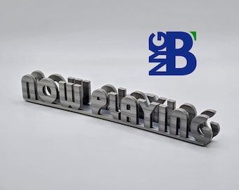 May include: A silver metal sign that reads "Now Playing". The sign is made of individual letters that are connected together.