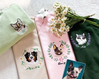 May include: A collection of pastel-colored sweatshirts, each embroidered with a pet portrait. The sweatshirts are light green, beige, pink, and dark green. The pet portraits include a cat, a dog, and a French bulldog. A photo of a French bulldog is also included.