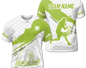 May include: White and green sublimated t-shirt with a pickleball player graphic and the text "Pickleball" and "TEAM NAME".