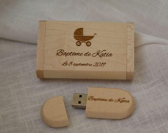 May include: A wooden USB flash drive and matching box. The box features an engraved baby carriage and the text "Baptême de Katia, Le 8 septembre 2019." The USB drive also has the text "Baptême de Katia."