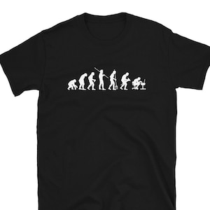 Op de afbeelding: Zwart t-shirt met een witte afbeelding die de evolutie van de mens weergeeft, eindigend met een persoon achter een computer. Het ontwerp toont de ontwikkeling van aap tot moderne computergebruiker.