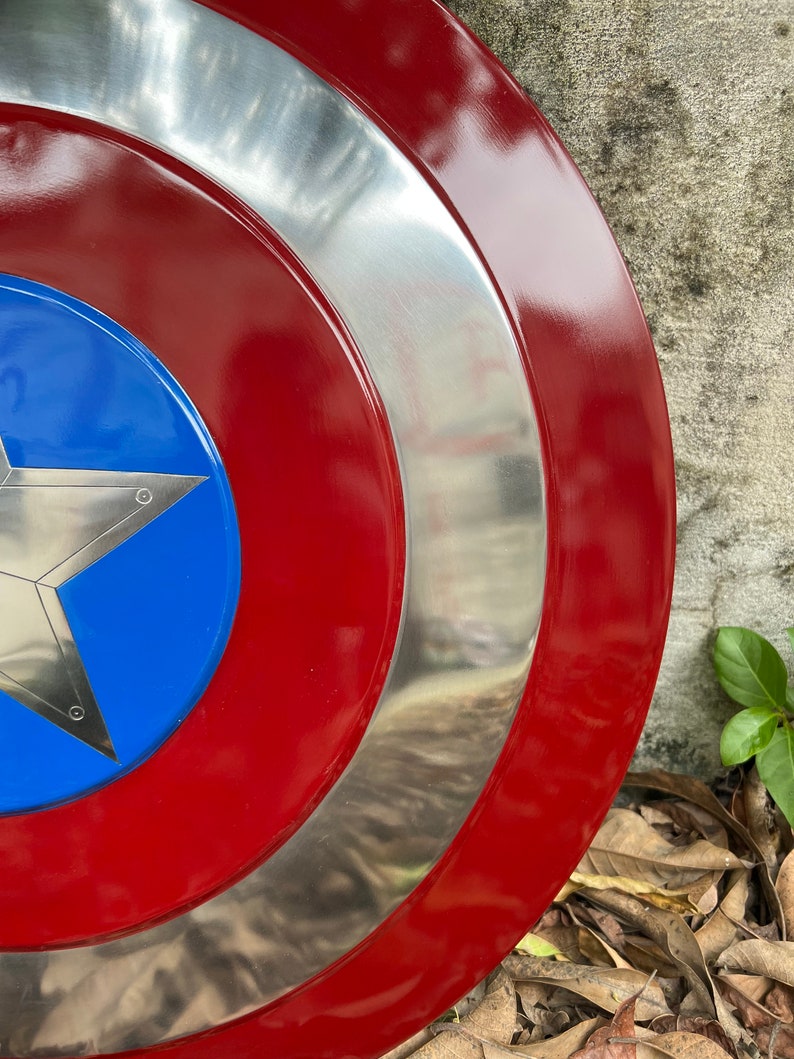 Op de afbeelding: Een rood, wit en blauw Captain America schild met een zilveren metalen rand. Het schild is gemaakt van metaal en heeft een ster in het midden.