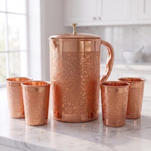 May include: A copper pitcher with a lid and four matching copper tumblers. Each piece features an intricate, embossed floral and vine pattern across the exterior surface. The pitcher has a curved handle and a small knob on the lid.
