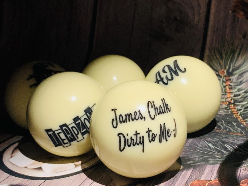 May include: Five white billiard balls with black lettering. The balls are arranged in a semi-circle. The text on the balls reads "TERPZONE", "James, Chalk Dirty to Me!" and "AM".