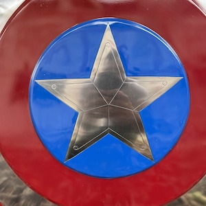 Op de afbeelding: Een rood, wit en blauw schild met een zilveren vijfpuntige ster in het midden. Het schild is een klassiek Amerikaans symbool.