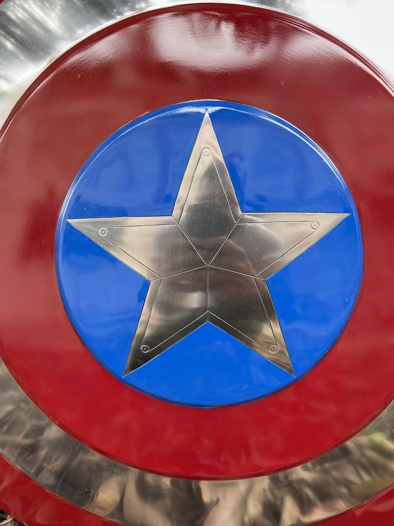 Op de afbeelding: Een rood, wit en blauw schild met een zilveren vijfpuntige ster in het midden. Het schild is een klassiek Amerikaans symbool.