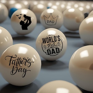 May include: White billiard balls with black lettering. The balls have different messages including "World's Best Dad", "Father's Day", and "Dad" with a crown.