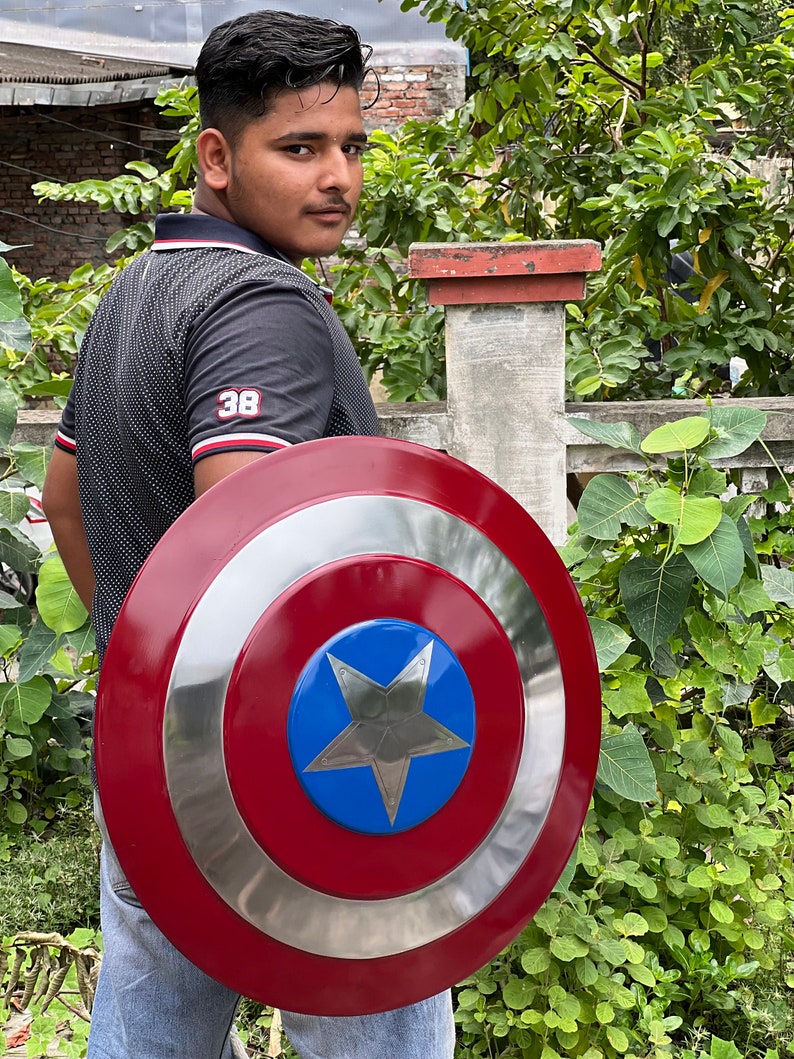 Op de afbeelding: Een persoon die een rood, wit en blauw Captain America schild vasthoudt. Het schild heeft een grote, vijfpuntige ster in het midden.