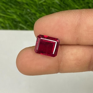 以下が含まれることがあります： 手のひらに置かれた深紅色のエメラルドカットの宝石