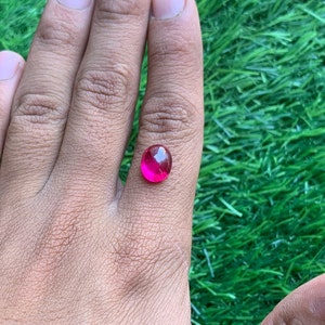 Op de afbeelding: Een ronde, felroze edelsteen met een gefacetteerd oppervlak.