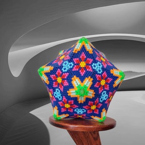 Puede incluir: Un adorno de cuentas con forma de estrella multicolor con un patr&oacute;n floral. El adorno est&aacute; hecho de peque&ntilde;as cuentas de colores y se muestra en un soporte de madera.