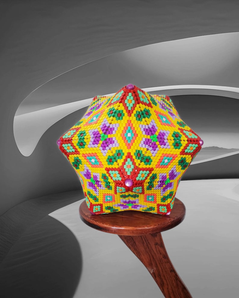 Puede incluir: Una escultura de cuentas geom&eacute;trica y colorida con una base en forma de estrella. La escultura est&aacute; hecha de peque&ntilde;as cuentas de colores en tonos de amarillo, verde, rojo, morado y naranja. Est&aacute; sentada en un taburete de madera.