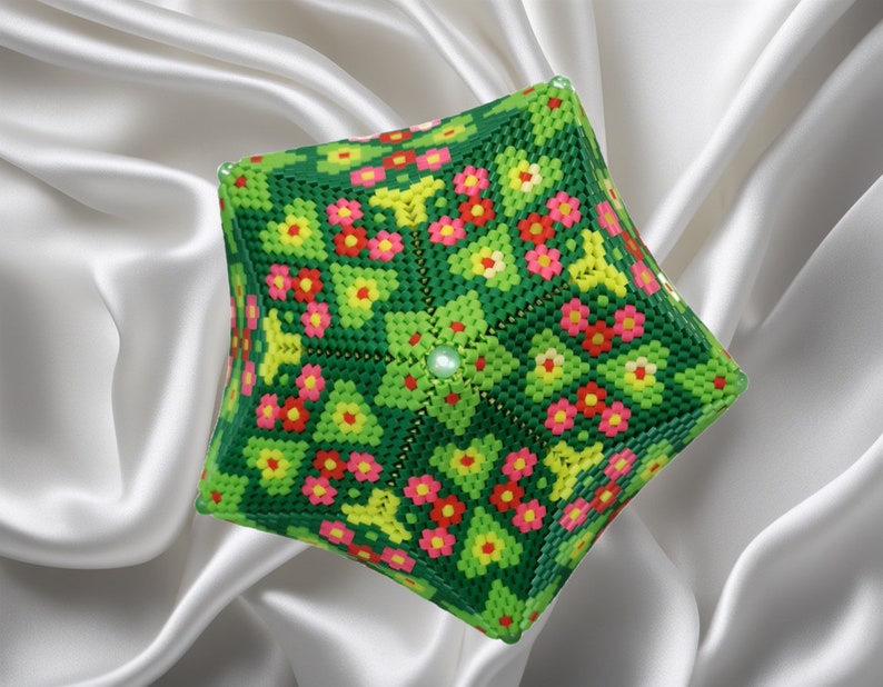 Puede incluir: Un cubo geom&eacute;trico verde, amarillo, rosa y rojo con cuentas con un patr&oacute;n floral. El cubo est&aacute; hecho de peque&ntilde;as cuentas de pl&aacute;stico y tiene un dise&ntilde;o sim&eacute;trico.